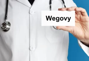 Lekarz prezentujący e-receptę na lek Wegovy na tle niebieskim, symbolizujący dostępność online przepisania leku na odchudzanie.